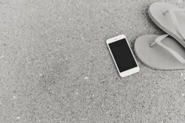 Smartphone cep telefonu ile plaj arka plan üzerinde siyah beyaz fotoğraf. Top düz yatıyordu stil closeup görüntülemek