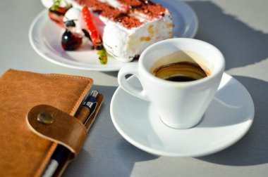 Kahve fincanı, çikolatalı kek ve masada açık defter. İş günü arka plan planlama.