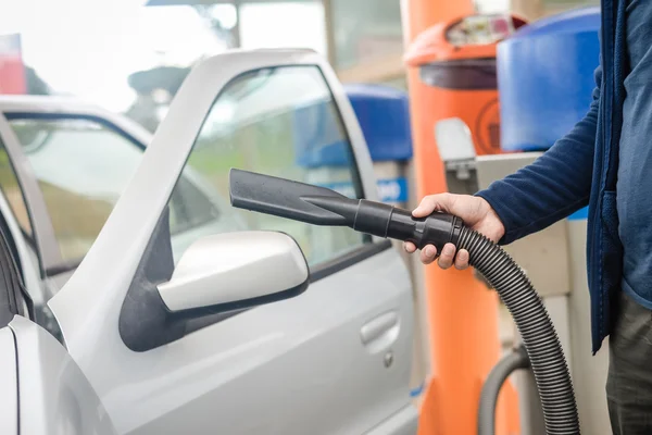 Manliga auto service arbetstagare dammsugning interiören i bilen. — Stockfoto