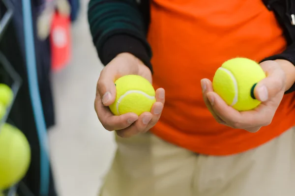 Nahaufnahme an der Hand mit Bällen für einen Tennisplatz vor dem Hintergrund eines Geschäfts — Stockfoto