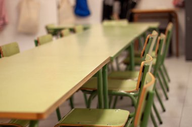 Okulun içi uzun bir masa ve birkaç yeşil sandalyeyle dolu, boş ve öğrenciler için hazır. Eğitim anlayışı, öğrenim ortamı ve okula dönüş