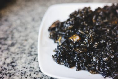 Mürekkep balığı mürekkebi ve deniz ürünleriyle pişirilmiş siyah pirinç, granit bir yüzey üzerinde beyaz bir tabakta servis ediliyor. Tipik bir Akdeniz yemeği. Derin rengi ve zengin tadı ile bilinir. İspanyol mutfağı, öğle yemeği ve ev yapımı yemekleri için mükemmeldir..
