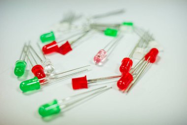 Close-up view of red and green LED diodes scattered on a clean white surface. Concept of technology, electronics, light emission, DIY projects, and hardware components.