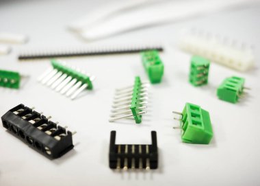Close-up image of assorted electronic connectors and green terminal blocks on a white background. Concept of electronics, prototyping, PCB design, and electrical components for industrial and educational use.
