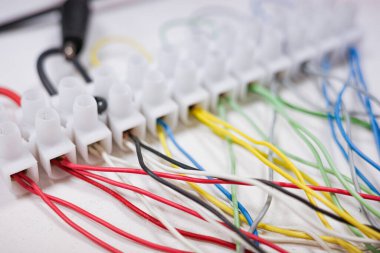 Plastik terminal şeridine bağlı çoklu renkli elektrik kablolarının teknik yakın çekimi. Çizim mühendisliği, DIY çalışması, kablo döşeme, enerji sistemleri, tamirat ve teknik eğitim için ideal.