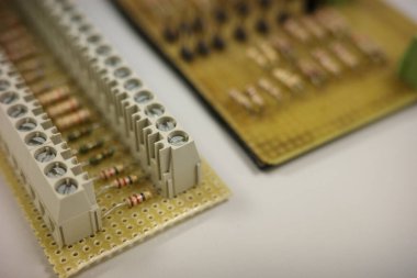 Elektronik bir prototip panonun makro görüntüsü. İçinde rezistanslar ve terminal blokları var. Görüntü, mühendislik, DIY elektroniği, prototip ve teknik kavramlar için ideal elektrik bileşenleri ve bağlantıları vurguluyor.