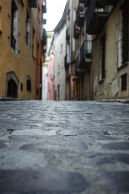 Tarihi bir kasabada dar bir kaldırım taşı sokağının alçak açılı perspektifi. Taş kaldırımlı geleneksel Avrupa mimarisi, seyahat, tarih, kentsel yaşam ve arka plan kavramları için ideal.