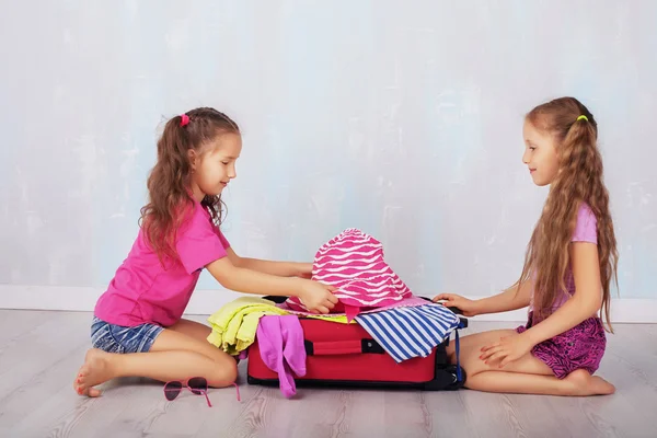 Děti, dvě dívky, shromážděte oblečení v kufru — Stock fotografie