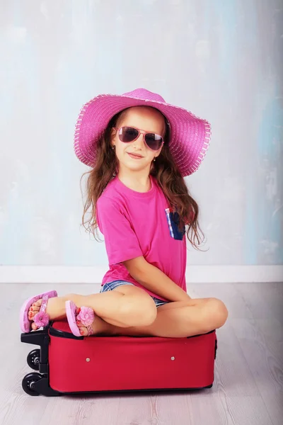 Hosszú hajjal, rózsaszín ül egy bőröndöt a gyermek — Stock Fotó