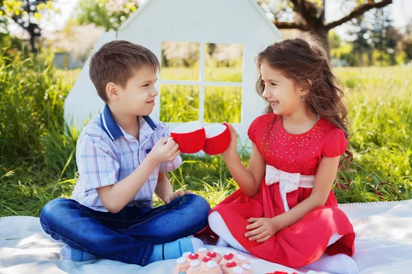 Красивая и милая маленькая девочка пьет чай с мальчиком на пикнике — стоковое фото