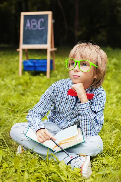 Snygg liten blond kille med glasögon mediterar — Stockfoto