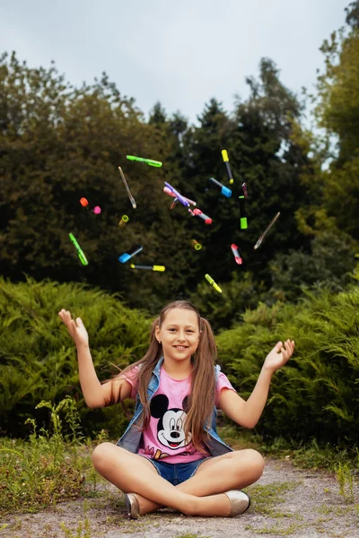 Skolflicka kastar upp pennor och markörer — Stockfoto