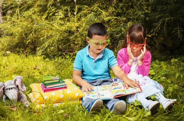 Niños, un niño y una niña leyendo un libro con gafas —  Fotos de Stock