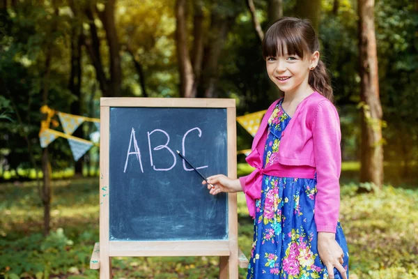 Vicces kislány azt tanítja az ábécé. A koncepció a tanulás és az iskolai — Stock Fotó