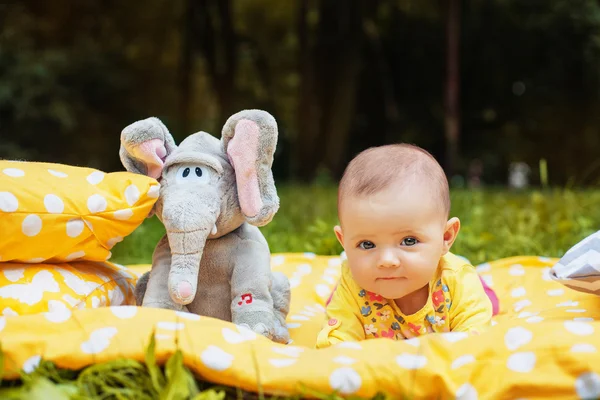 Hermosa nena acostada en una cortina amarilla en un parque con elefantes — Foto de Stock