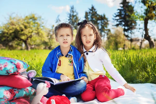 Gyermek, egy fiú és egy lány a kertben könyvet olvasva — Stock Fotó