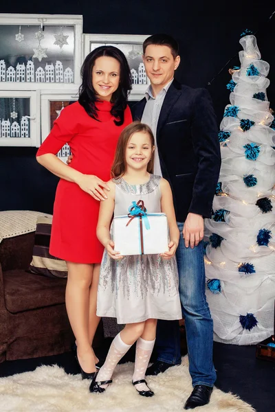 Familia feliz, madre, padre e hija, de pie cerca de un árbol de Navidad. El concepto del Año Nuevo y Feliz Navidad — Foto de Stock