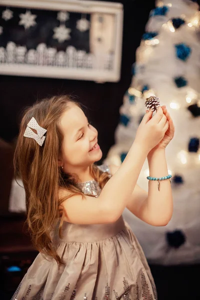 コーンを持つ美しい小さな女の子。新年とメリークリスマスのコンセプト — ストック写真