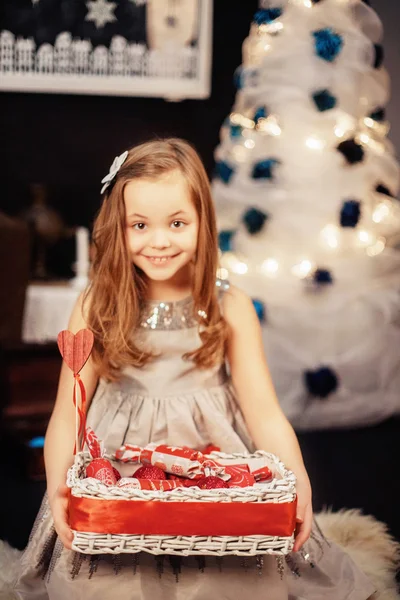 お菓子とバスケットを持つ美しい小さな女の子。新年とメリークリスマスのコンセプト — ストック写真