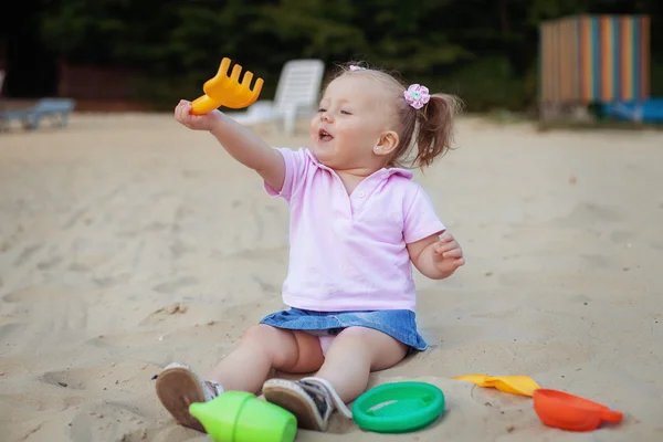 Hermosa niña jugando en el rastrillo de la caja de arena. El concepto o — Foto de Stock