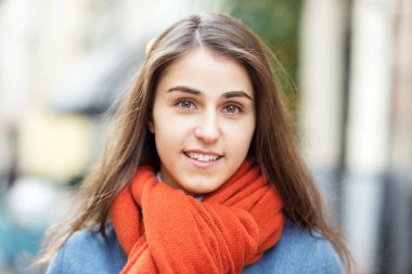 Şapka ve eşarp takmış bir kızın portresi, Noel şehrinde bir yürüyüş, yüzünde bir gülümseme, serin hava, büyüleyici bir görünüş..