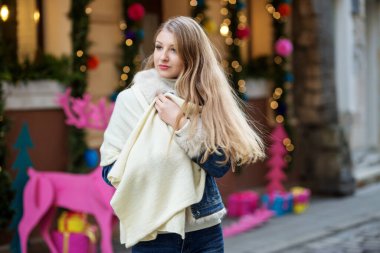 Kanat çırpan atkısı olan mutlu genç kız şehrin Noel sokaklarında yürüyor. Zarafet ve hafif adımlar, kış satışlarının mutluluğu..