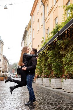 Siyah ceketli genç bir çift şehrin sokaklarında yürüyor, mutlu bir çift, romantik bir randevu..