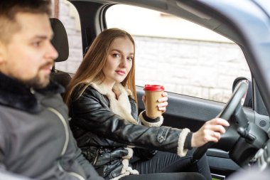 Bir kız ve bir adam siyah bir arabada oturuyor, bir kız sürüyor, iyi bir sürücü, araba sürmeyi öğreniyor. İş kadını kavramı, araba sürmeyi öğrenen bir kız..