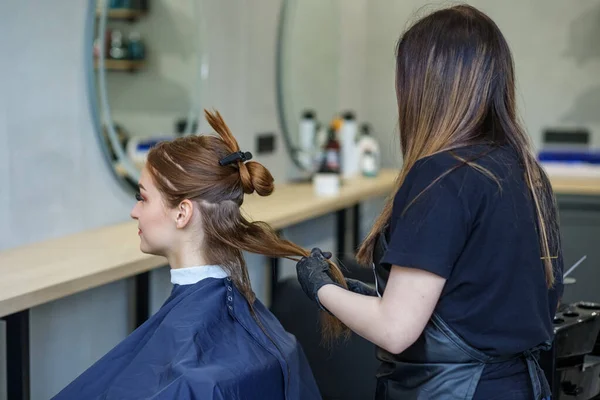 Le coiffeur fera le coiffage à la jeune femme dans le salon de beauté. — Photo