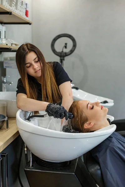 Flickan tvättas håret i frisören efter målning. Semester koncept, hårvård, bild förändring. — Stockfoto