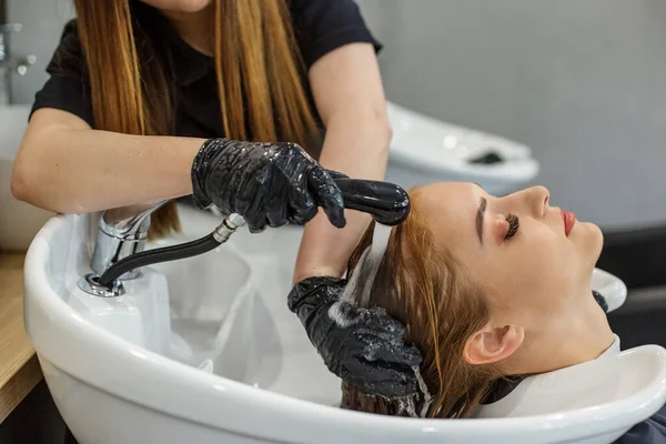 Flickan tvättas håret i frisören. Avkopplingskoncept, hårvård, bildförändring. — Stockfoto