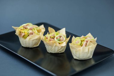 Siyah tabakta ton balıklı ve soğanlı üç tart, açık büfe mezesi..