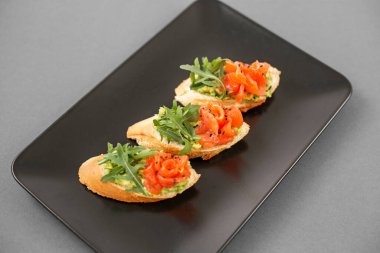 Büfeden gelen turta, siyah tabakta, kırmızı balık ve roka ana yemekten önce lezzetli bir aperatif..
