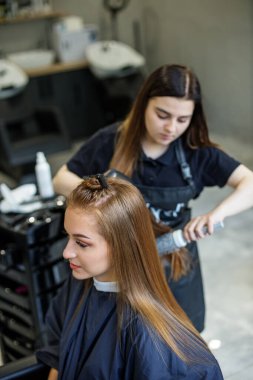 Berber saçını kurutur, uzun saçlı bir kıza saçını keser. Bir kadın saçını boyar, saçını saç kurutma makinesiyle kurutur..