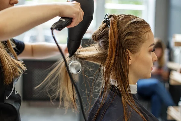 A fodrász megszárítja a haját. Egy lány egy szépségszalonban, egy fodrász megcsinálja a haját, levágja a haját egy hosszú hajú lánynak.. — Stock Fotó
