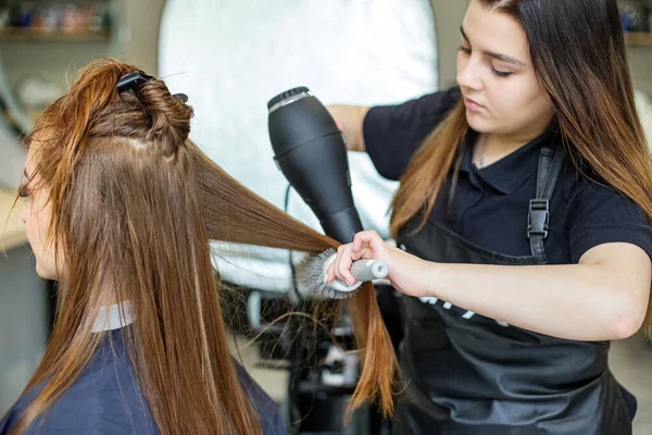 A fodrász megszárítja a haját. Egy lány egy szépségszalonban, egy fodrász megcsinálja a haját, levágja a haját egy hosszú hajú lánynak.. — Stock Fotó