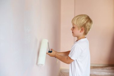 Mutlu çocuk ebeveynlerin duvar boyamasına yardım eder. Aile için yeni bir ev. Ev tadilatı. Çocuk tadilat sırasında eğleniyor.