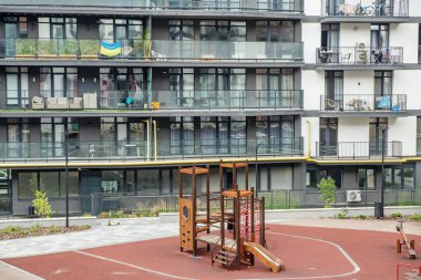 Çağdaş apartman kompleksinin önündeki şehir oyun alanı, çocuklar için tırmanma yapıları, kayma ve güvenli zemin.