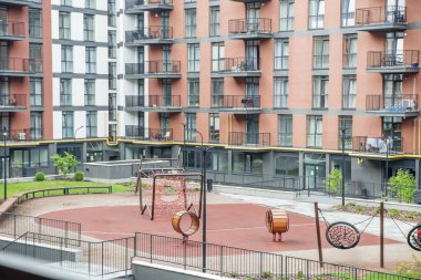 Etrafı kentsel apartmanlarla çevrili bahçe bahçesinde tırmanma ağları ve bahar oyuncakları olan güvenli ve renkli bir oyun alanı..