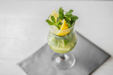 Alkolsüz soğuk bir narenciye, limon, nane ve buzlu moktail. Gri peçetede uzun bir bardakta..