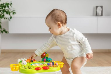 Genç çocuk evde renkli bir aktivite masasıyla meşgul oluyor, motor becerilerini geliştiriyor ve elle oynanan oyunlarla öğreniyor..