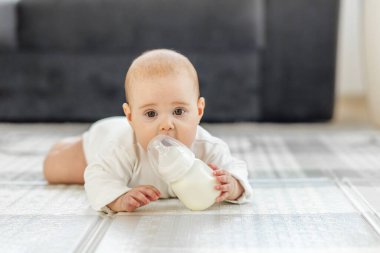 Evde yerde yatarken Şişe 'den Şirin Bebek İçen Süt. Bebek bakımı