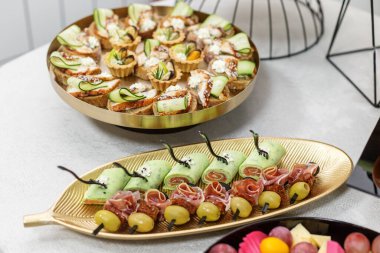 Şık bir yemek davetinde sunulan somon ambalajlı, prosciutto şiş, zeytin ve gurme kanepeli lüks parti yemeği tabağı.