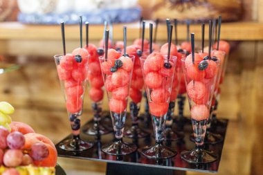 Yaz partisinde karpuz topları ve yaban mersinli mini bardaklarla servis edilen zarif yemek servisi..