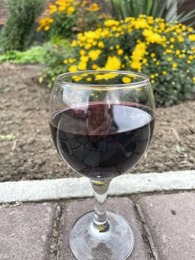 glass of red wine on the cobblestones, autumn yellow chrysanthemum flowers, beautiful
