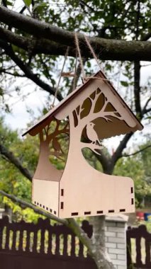 bird feeder on a tree in a Ukrainian autumn garden, tiny plywood house