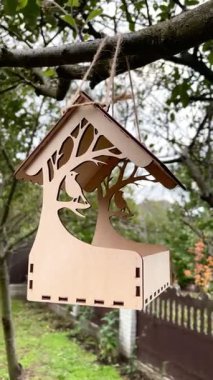 bird feeder on a tree in a Ukrainian autumn garden, tiny plywood house