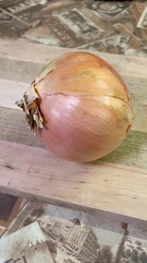 Tahtanın üzerinde büyük kahverengi bir soğan yatıyor..