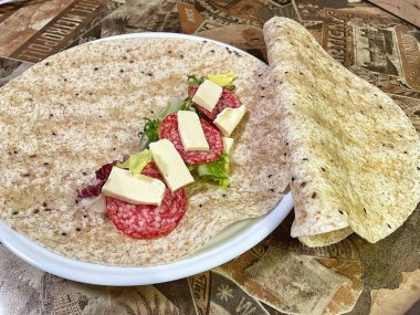 Lavaş tabakları, lavaş tortilla, işlenmiş peynir, sosis, yeşillik.
