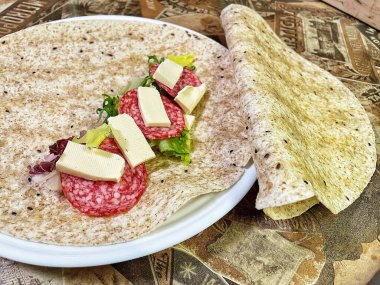 Lavaş tabakları, lavaş tortilla, işlenmiş peynir, sosis, yeşillik.